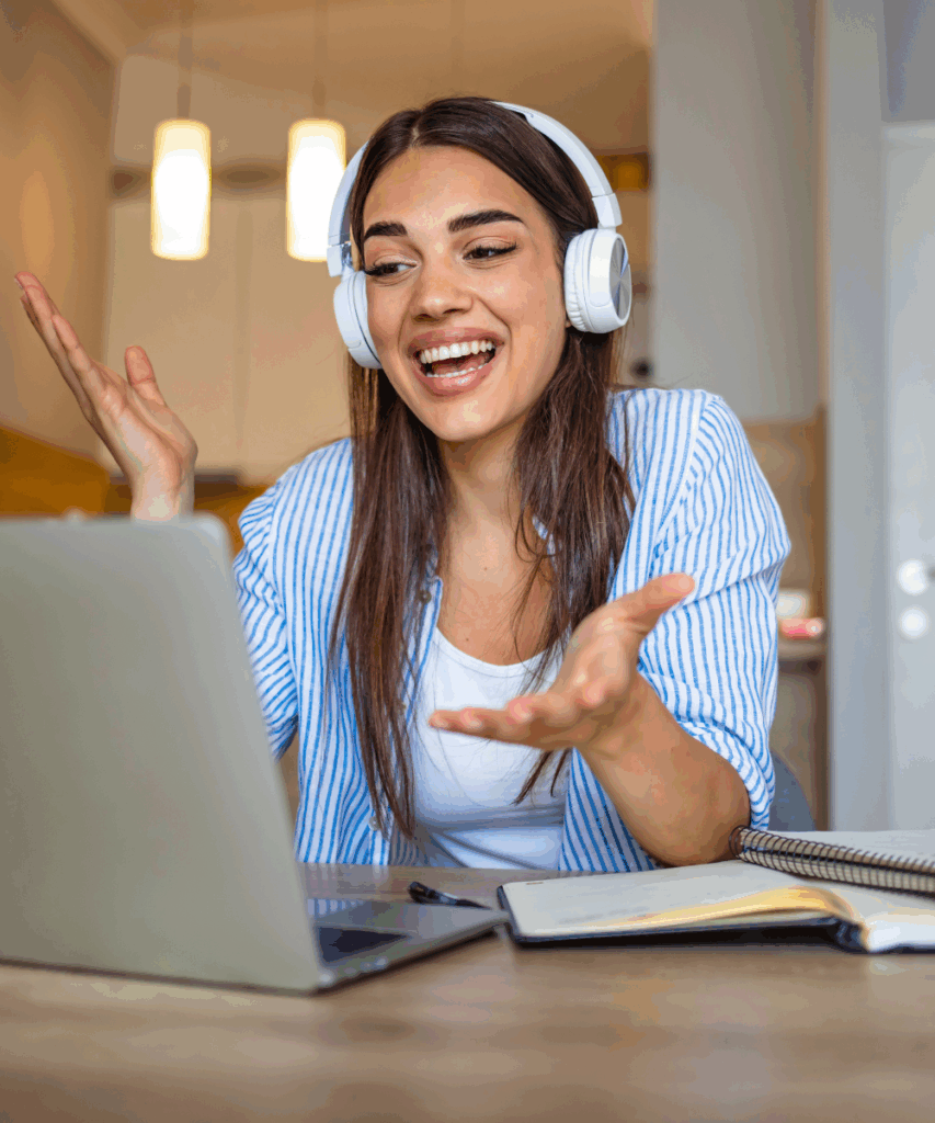 A person in white headphones and a blue stripy shirt with long hair delivering training in front of a laptop.