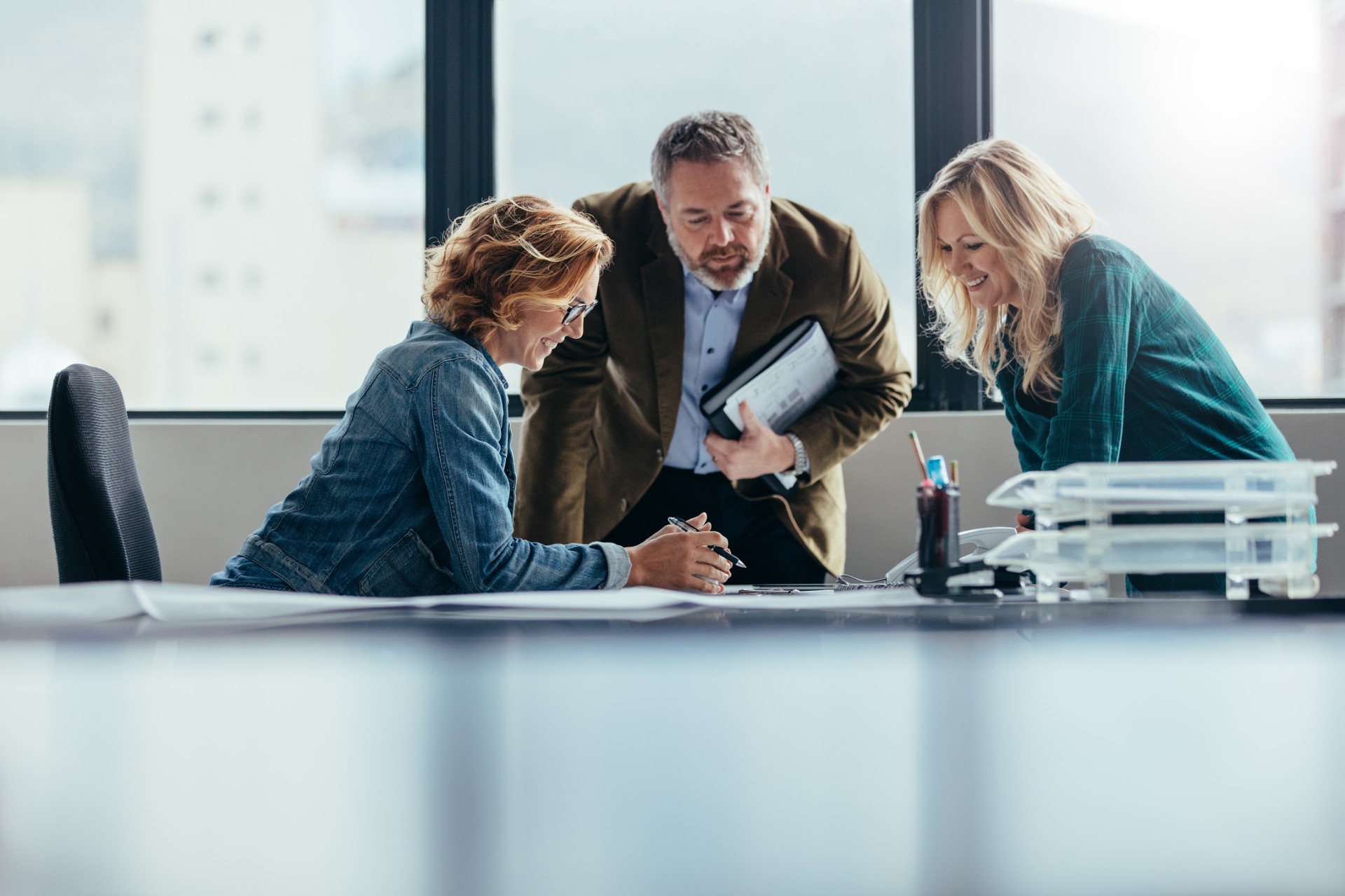 Three colleagues leaning over consultation plans spread across a meeting table