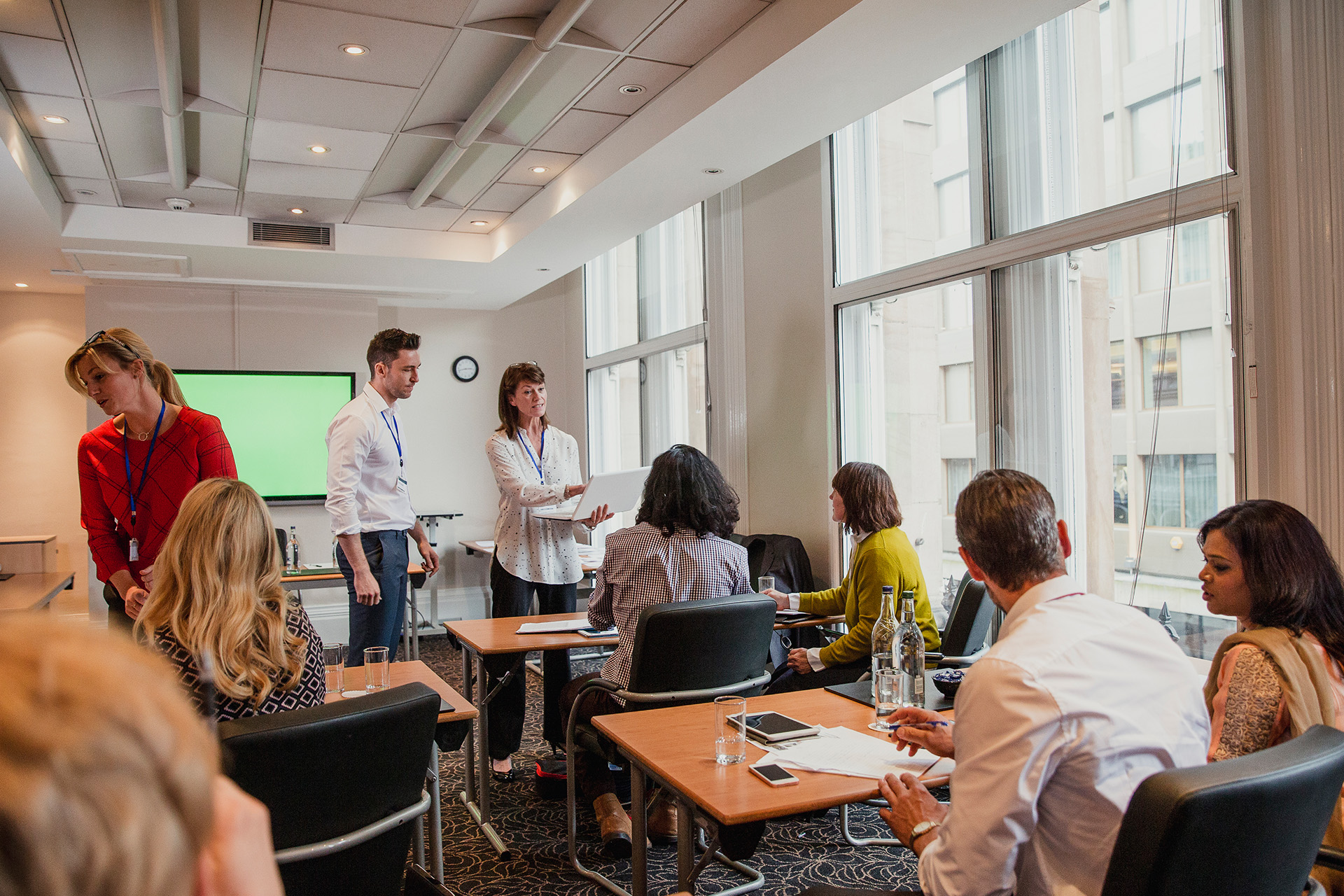 A colleague at a flipchart turning to answer two people seated at the table