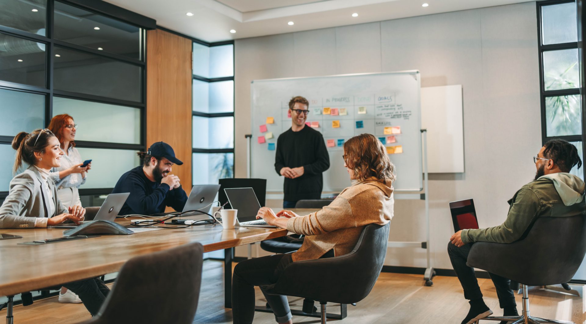 A facilitator working through sticky notes on a whiteboard with a seated group