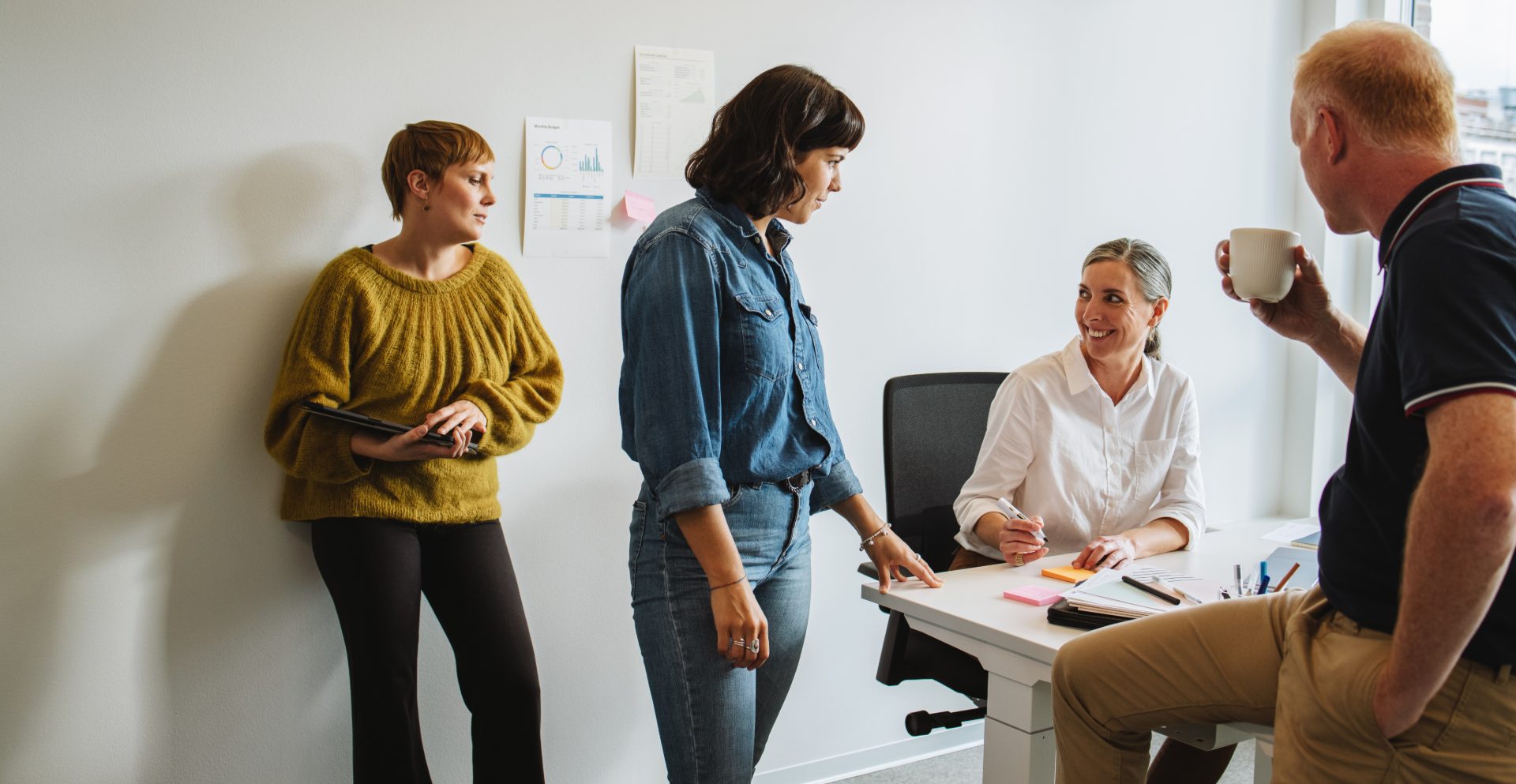 A small team talking around a desk with coffee