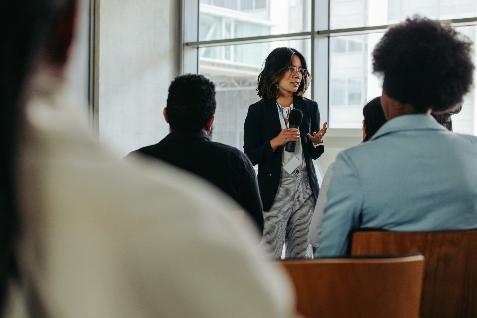A facilitator with a microphone addressing a seated audience