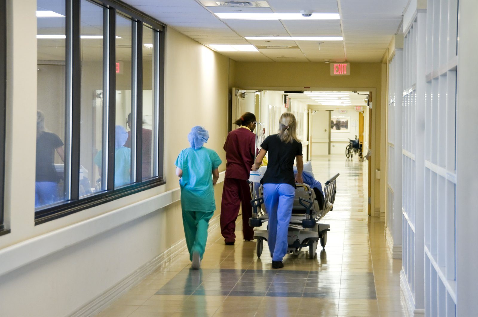 Hospital staff moving a patient along a ward corridor