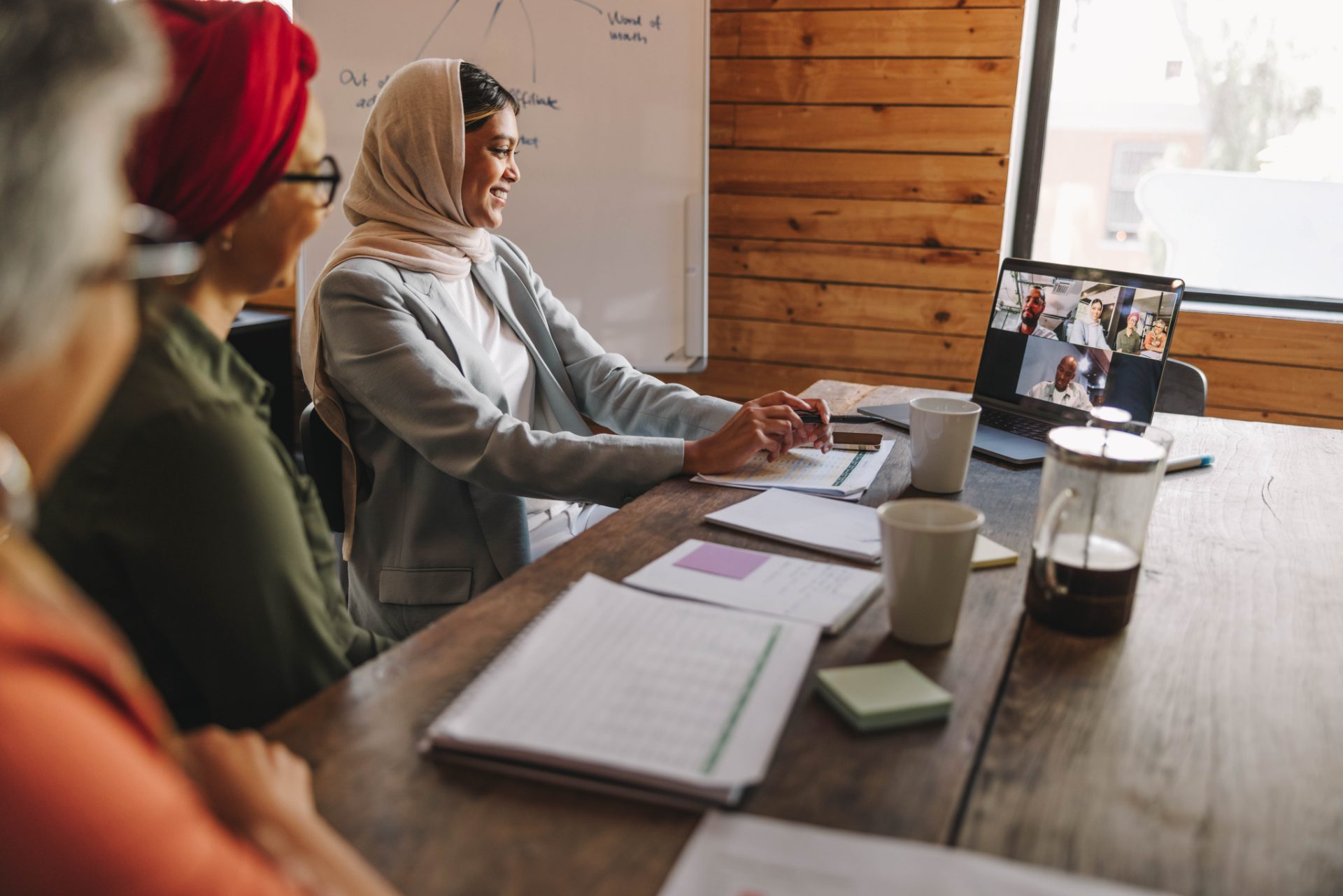 Colleagues around a meeting table joining a Coffee Morning on a video call